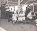 September 6, 1959 Meadowdale, IL. Driver Rodger Ward talks with Ralph Wilke. Ward, wheeling his Leader Card 110 Offy, midget #16 in background, set a track record during time trials, getting around the Meadowdale Road course with an average speed of 92.271 miles per hour. Also in the background is Larry Shinoda noted American automotive designer who was best known for his work on the Corvette and Ford Mustang. Larry a longtime crew member and family friend, also designed cars with AJ Watson.