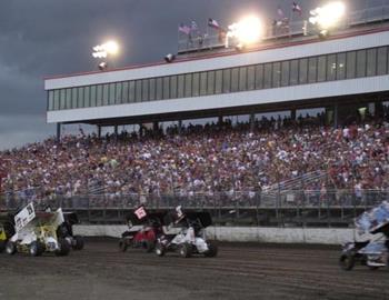 A heat race charges down the frontstretch before a packed house.